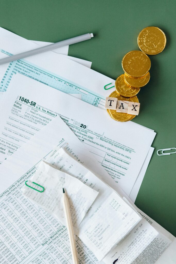 pexels photo 6863182 6863182 Tax documents and gold coins on a green desk symbolizing financial planning and savings.
